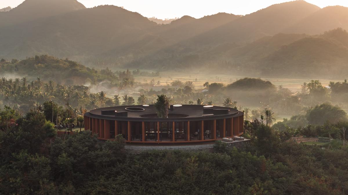 A circular pavilion on a hilltop at sunrise, with mist over the valley behind